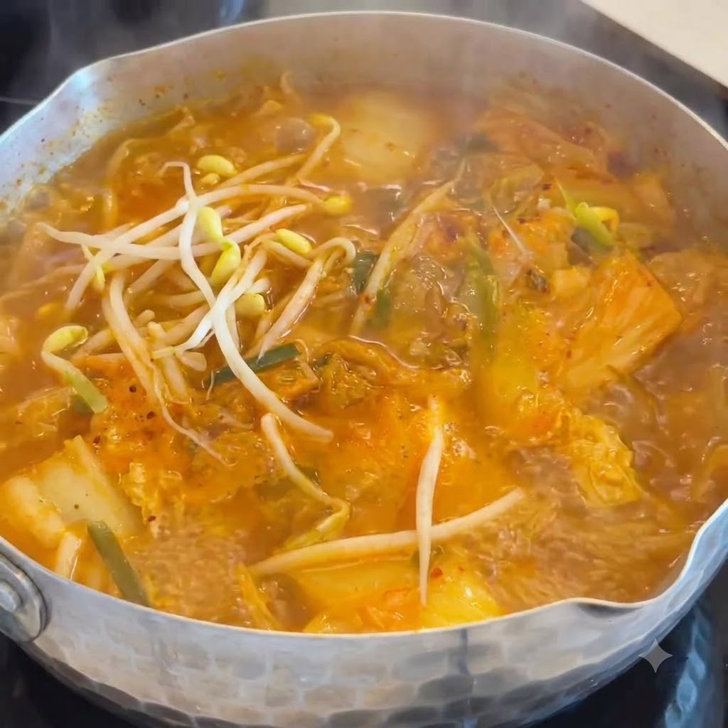 Germogli di soia bianchi e croccanti versati in una pentola di zuppa arancione che sobbolle.