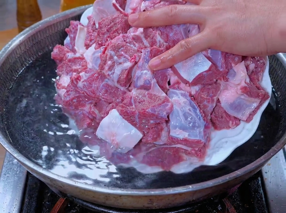 Pezzi di manzo messi in ammollo aggiunti a una pentola dacqua per la sbollentatura.