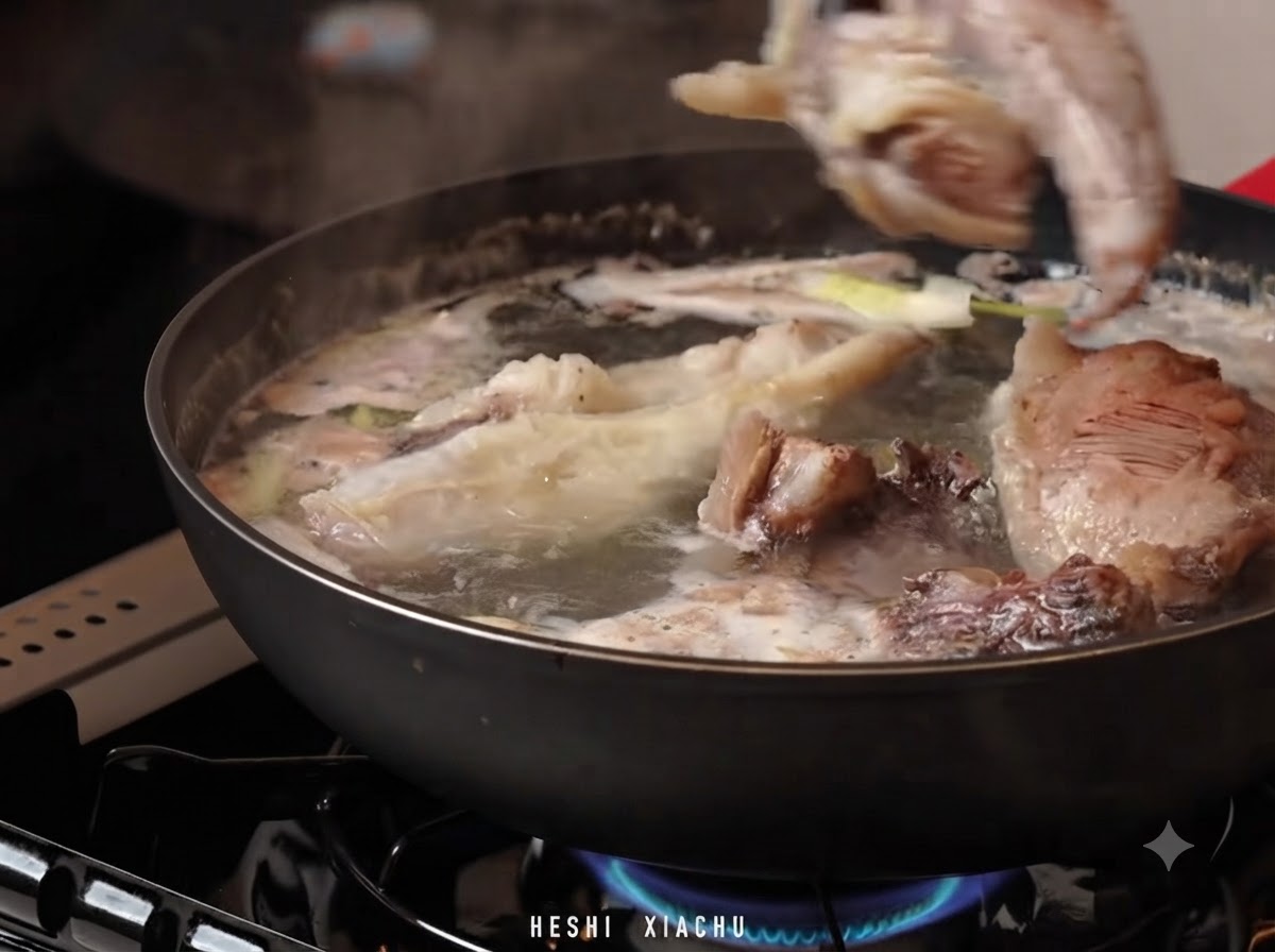 Pezzi di braciere di manzo trasferiti in una pentola di acqua calda con brodo di zuppa e aromi.