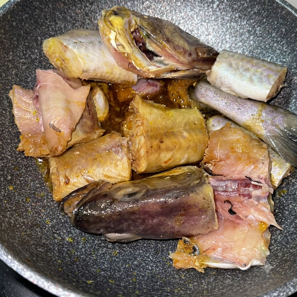 Pezzi di merluzzo che rosolano nella padella insieme a patate gialle affettate.
