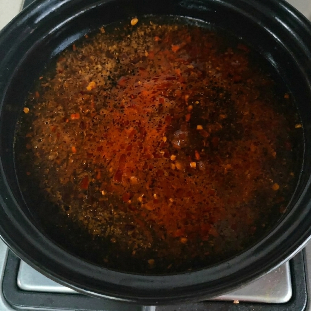 Condimento in polvere di manzo cosparso sulla superficie della zuppa che bolle.