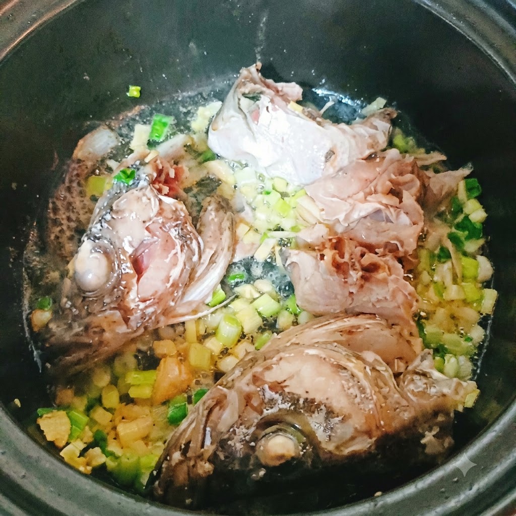 Pezzi di pesce merluzzo e testa che friggono in una pentola con aromi tritati.