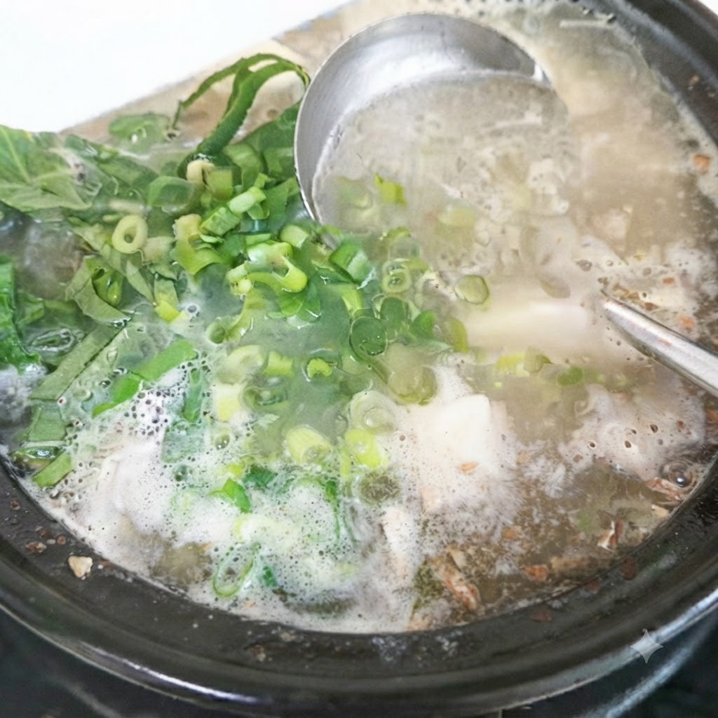 Foglie di perilla fresca e cipollotti tritati aggiunti alla pentola della zuppa finita.