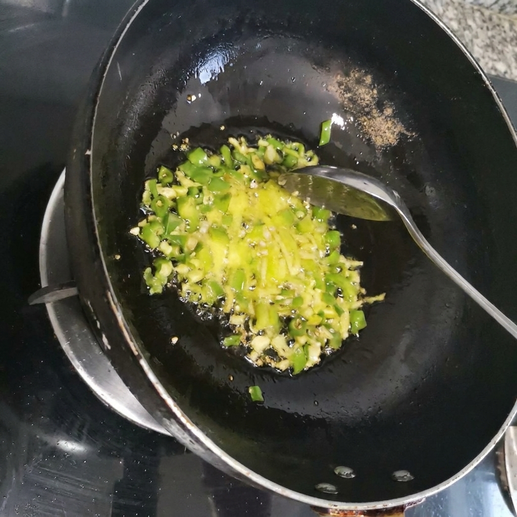 Peperoncino rosso tagliato a julienne fatto saltare in padella con aromi verdi allinterno di un wok scuro.