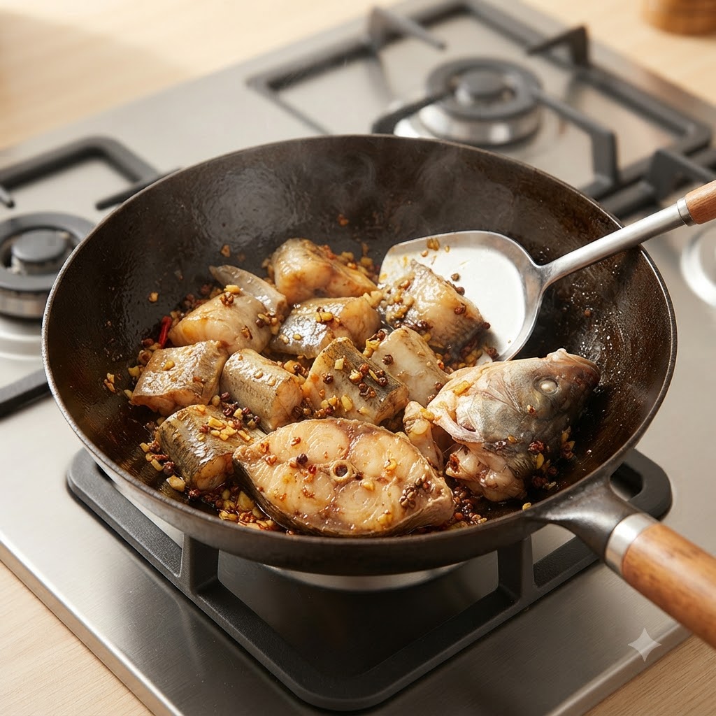 Pezzi di pesce merluzzo fatti saltare con gli aromi allinterno di un wok usando una spatola di metallo.