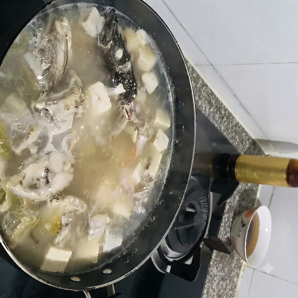 Condimenti aggiunti a una pentola ribollente di zuppa di pesce con tofu.
