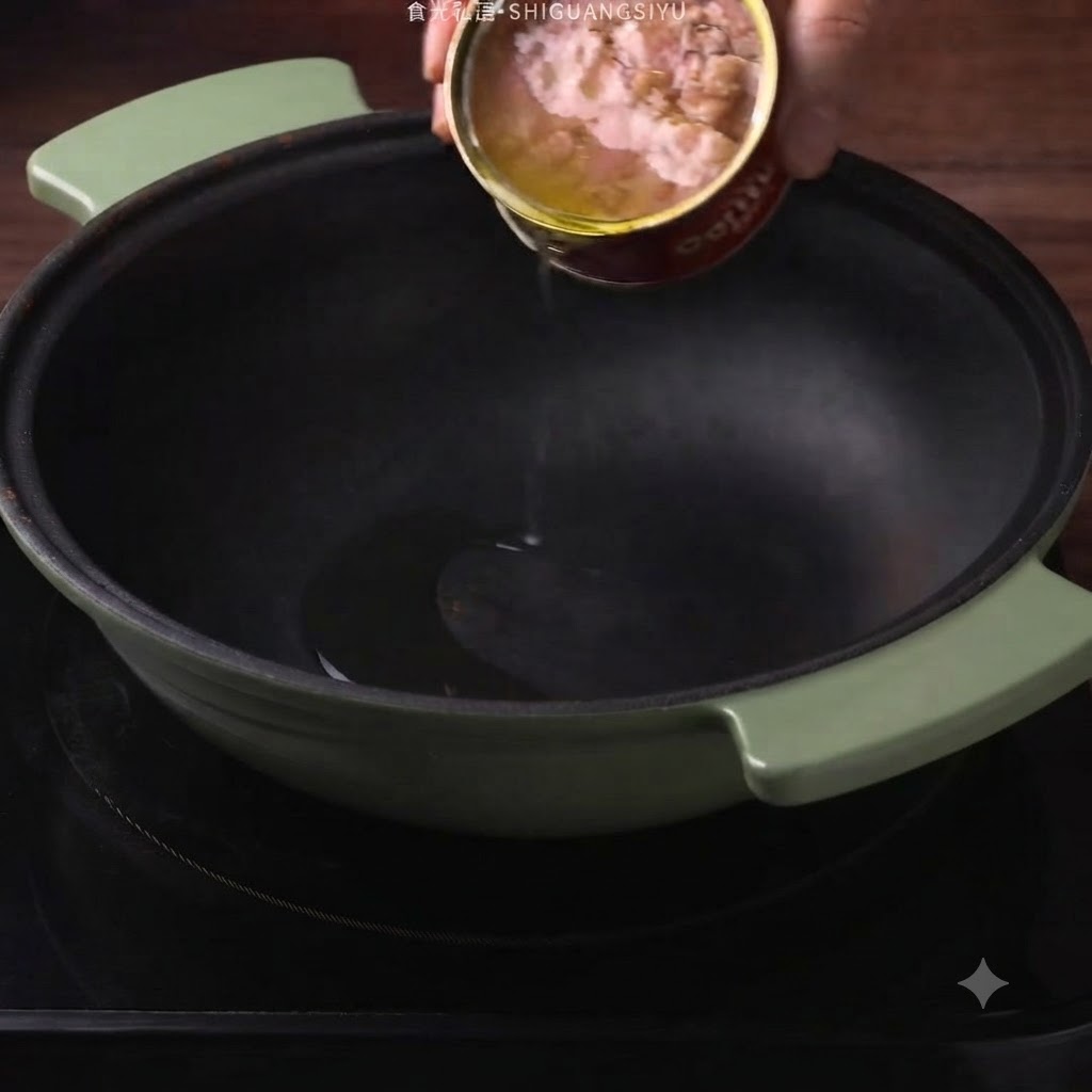Lolio di tonno in scatola viene versato da una scatola in una pentola verde scuro.