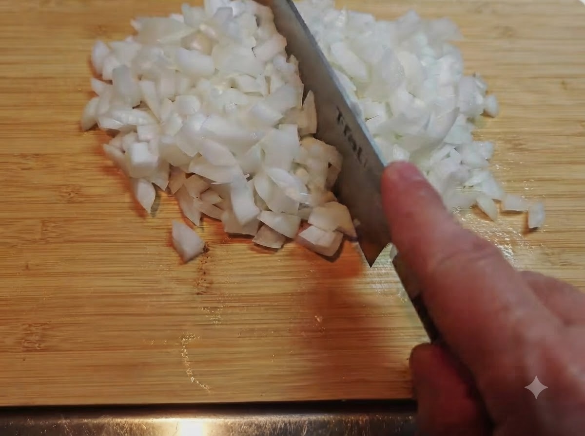 Un mucchio di cipolle bianche finemente tritate con un coltello su un tagliere di bambù.