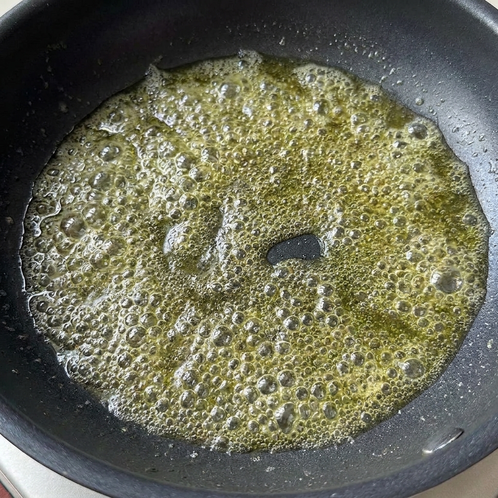 Salsa di soia leggera e concentrato di pomodoro aggiunti al burro fuso che sobbolle in una padella.