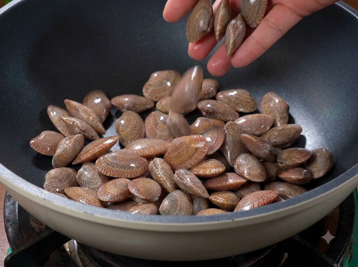 Vongole gettate in un wok caldo e asciutto sul fuoco.
