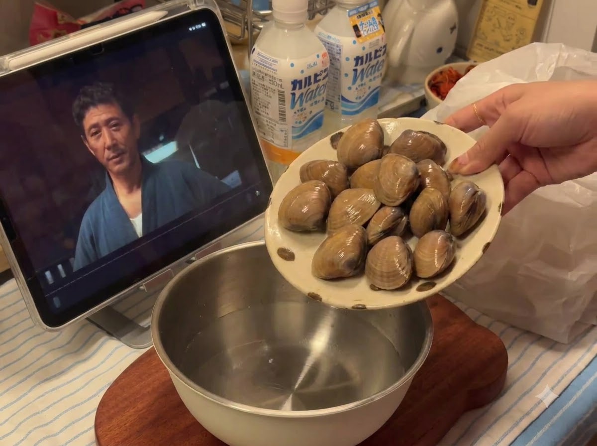 Vongole fresche versate da un piatto in una ciotola di metallo con acqua.
