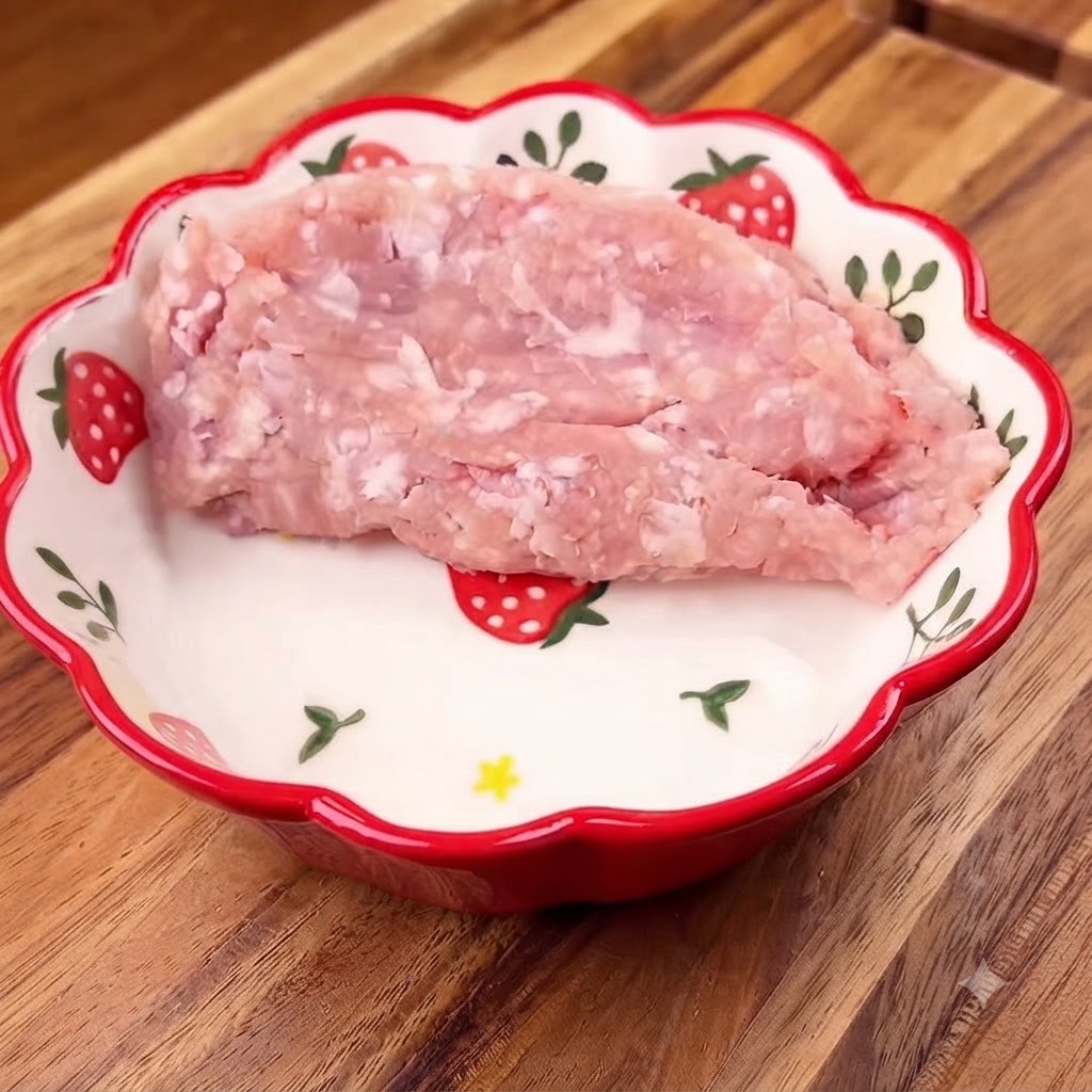 Maiale macinato posizionato allinterno di una ciotola floreale con cipollotti tritati sopra.