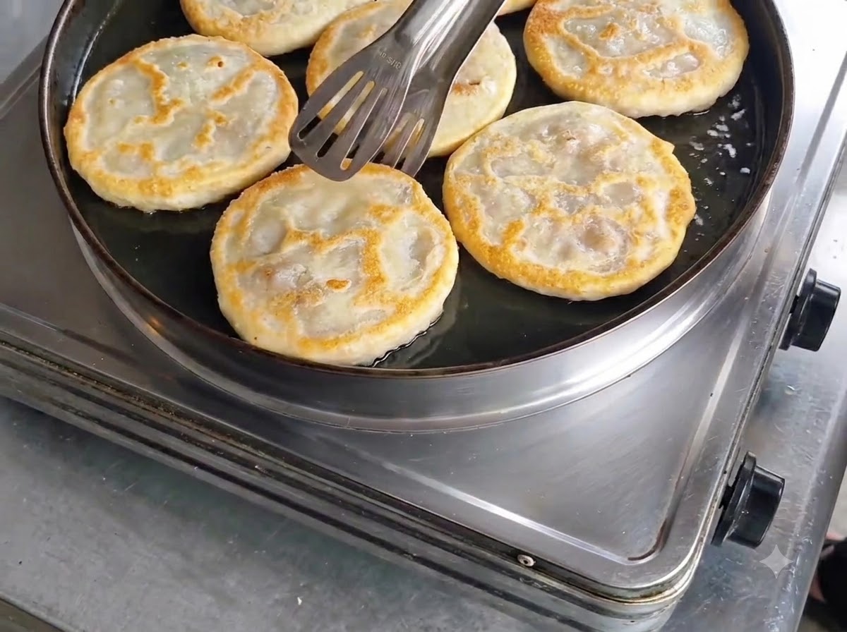 Panzerotti di carne cotti e dorati controllati con le pinze nella padella prima della rimozione.