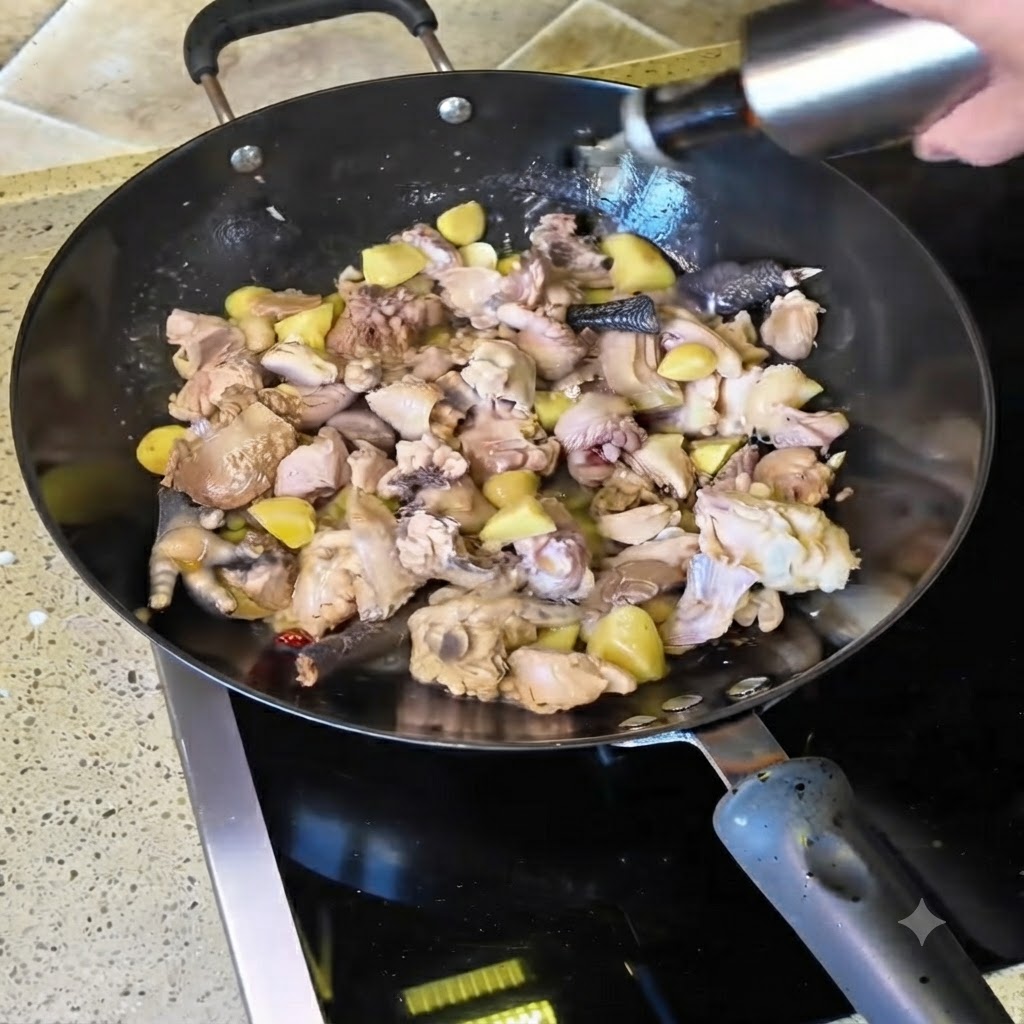 Vino giallo versato da una bottiglia nel wok pieno di pezzi di pollo saltati.