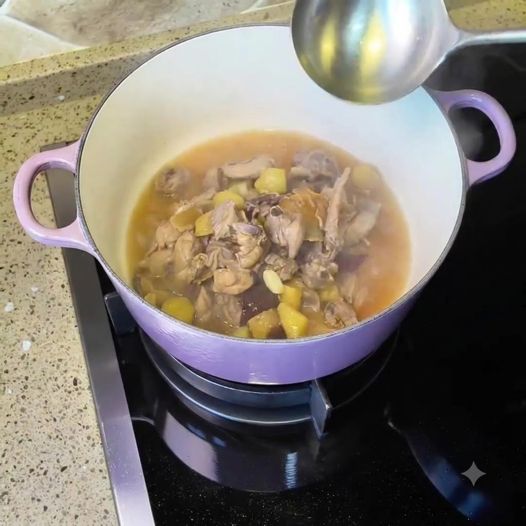 Pollo e zuppa che sobbollono dentro una pentola di ghisa viola sul fuoco con un mestolo.