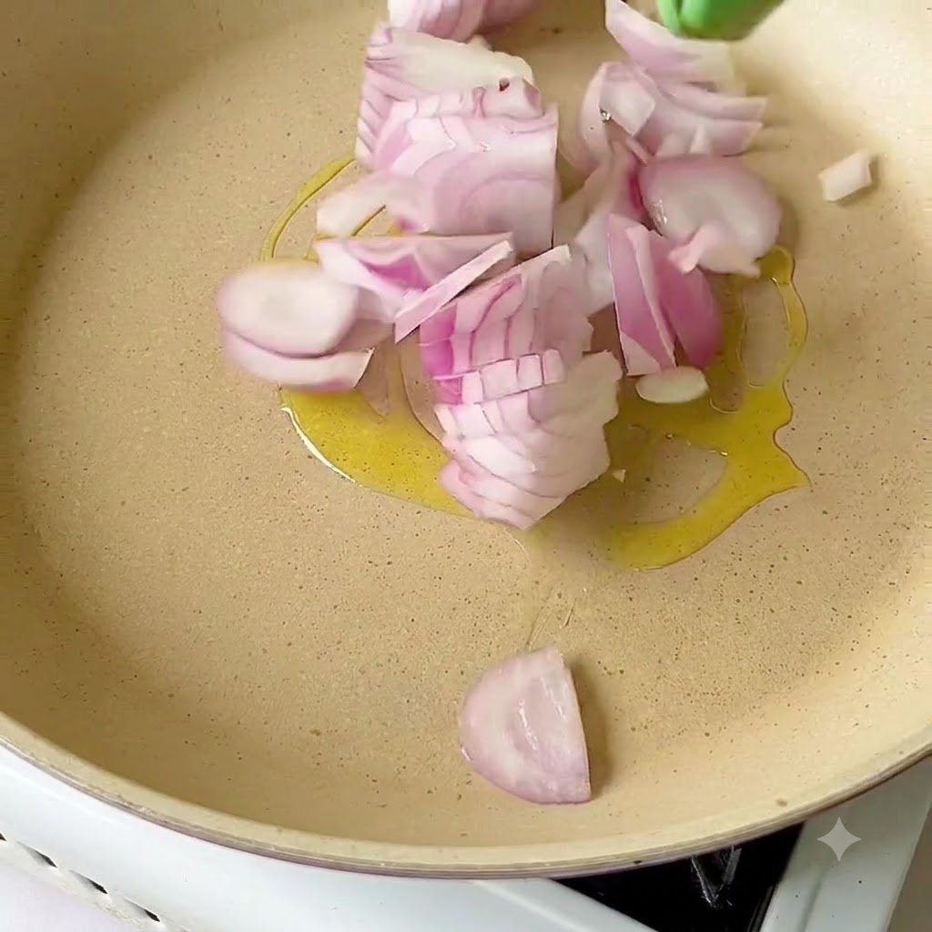 Cipolle rosse affettate che sfrigolano nellolio doliva dentro una padella.