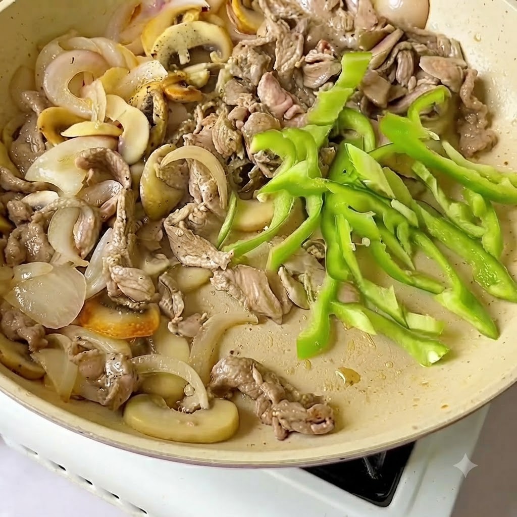 Fette di peperone verde fresco aggiunte alla padella insieme a manzo e cipolle.
