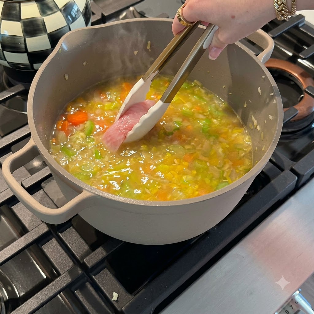 Filetti di petto di pollo crudo posti in una pentola di verdure ribollenti e brodo di ossa usando pinze con punte in silicone.