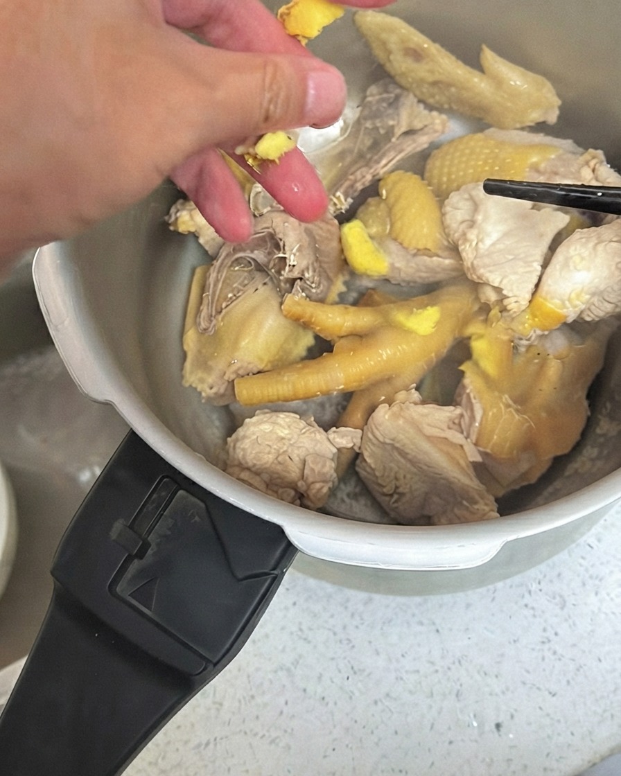 Pezzi di zenzero schiacciato sparsi sopra il pollo allinterno di una pentola a pressione.