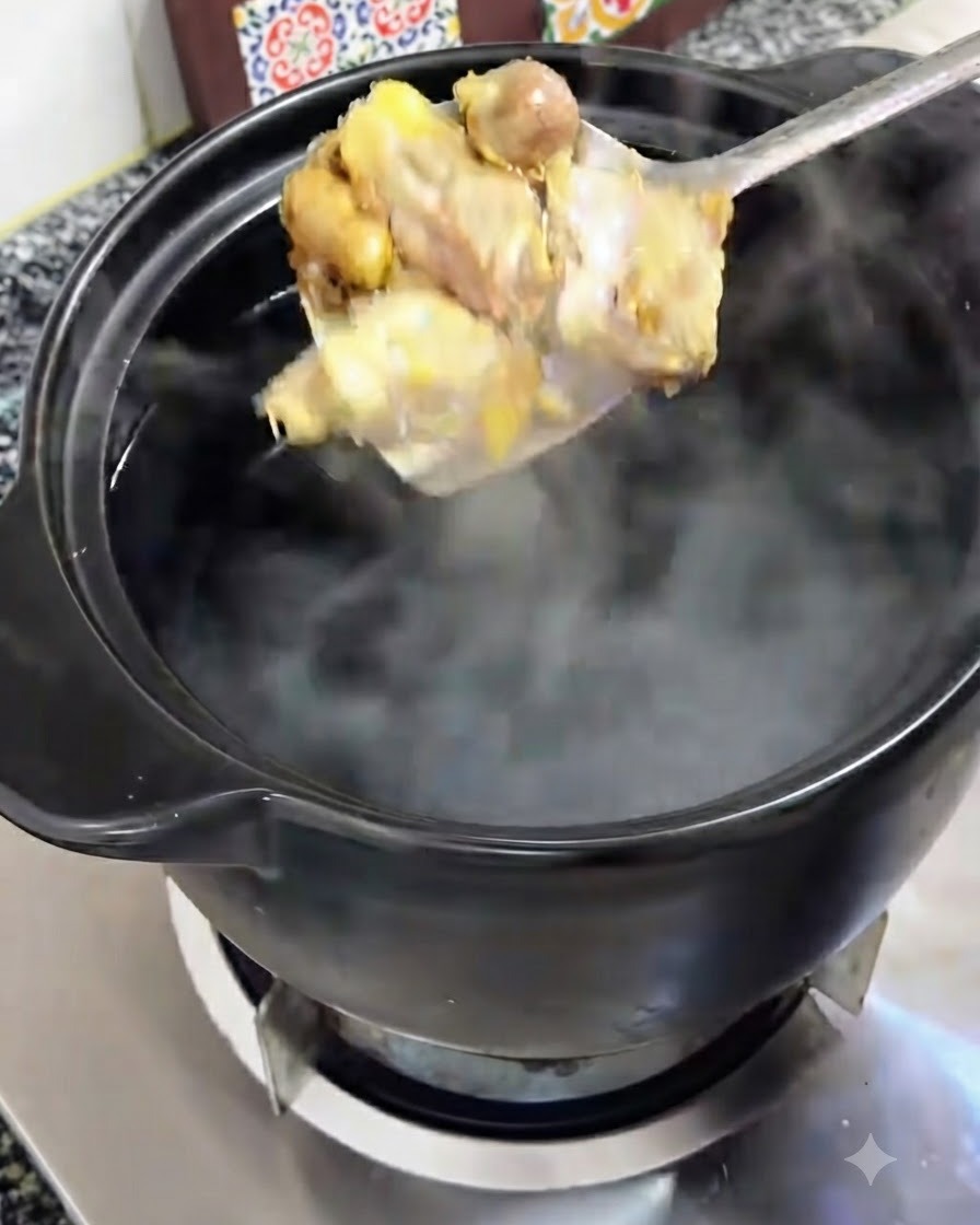 Pezzi di pollo dorati sollevati su un cucchiaio e trasferiti in una pentola di terracotta nera con acqua bollente.