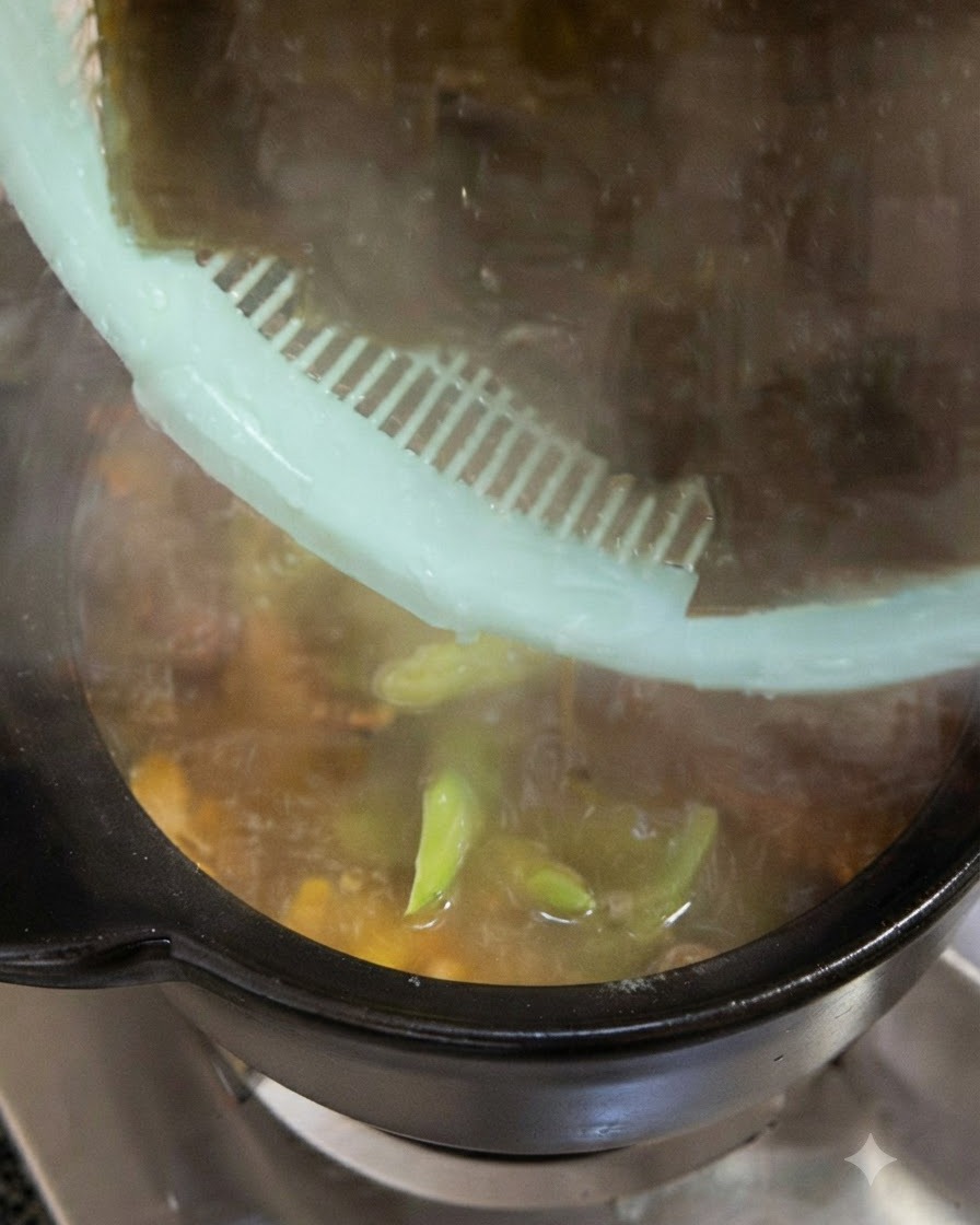 Grandi pezzi di alga kelp verde scuro messa in ammollo aggiunti nella pentola di cottura da un colino verde.