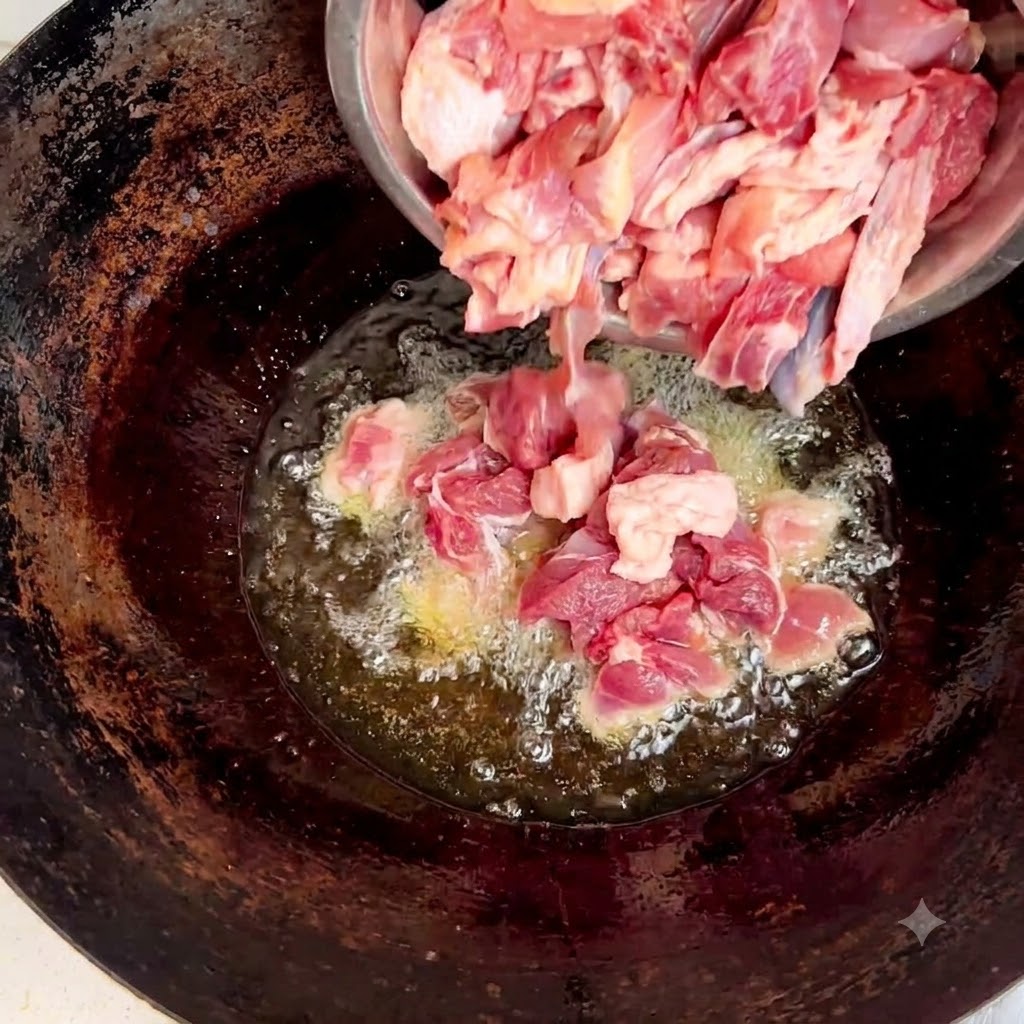 Pezzi di pollo crudo versati da una ciotola dacciaio in un wok con olio e zenzero.