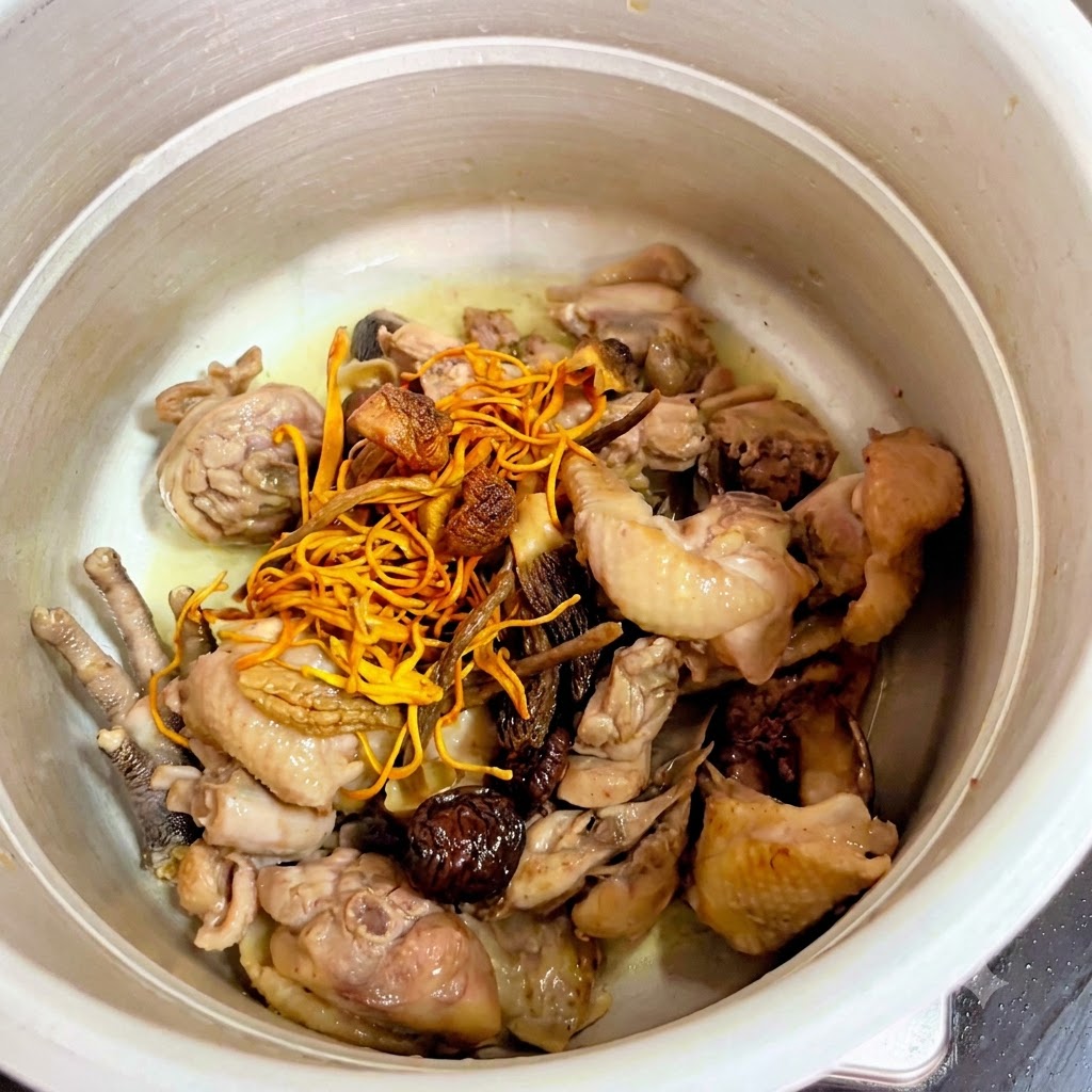 Funghi essiccati e fiori di cordyceps gialli posizionati sopra il pollo allinterno della pentola a pressione.