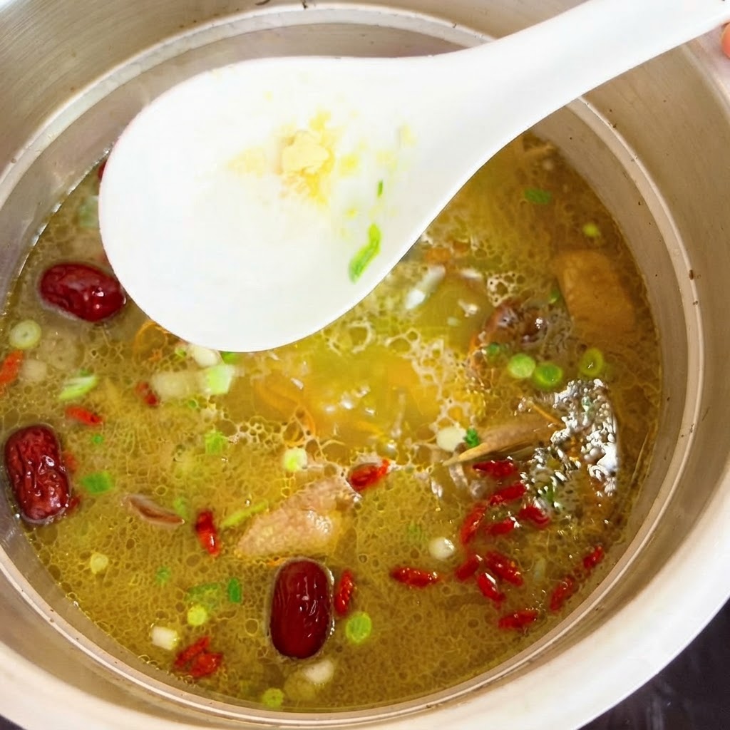 Essenza di pollo mescolata nel brodo di pollo caldo con un cucchiaio bianco.