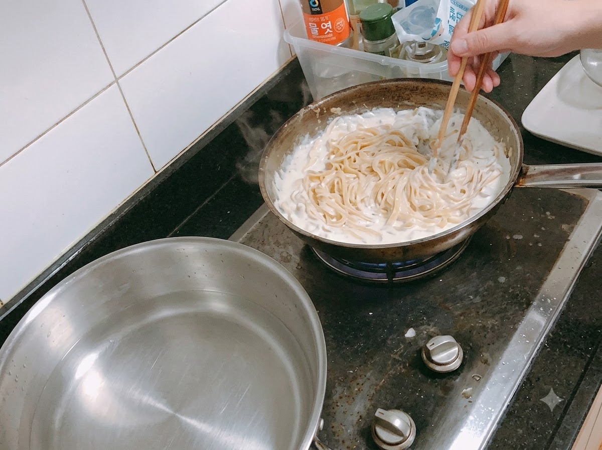 Pasta mescolata in una salsa cremosa in padella usando un forchettone.