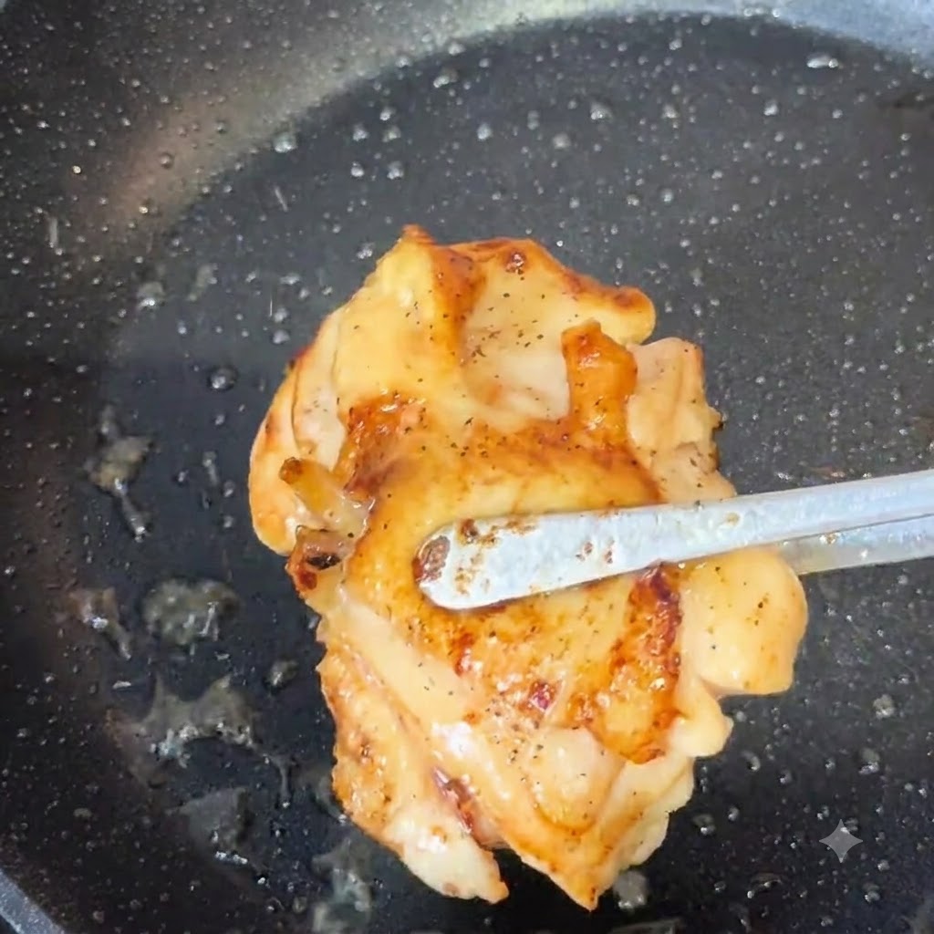 Dindo pinze che sollevano una coscia di pollo cotta e dorata da una padella.