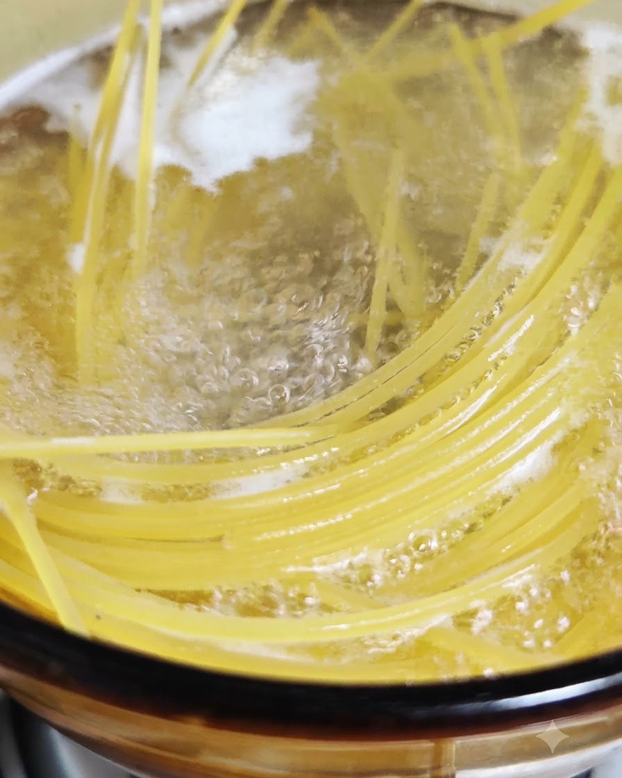 Spaghetti in cottura che bollono in una pentola di acqua bollente salata.