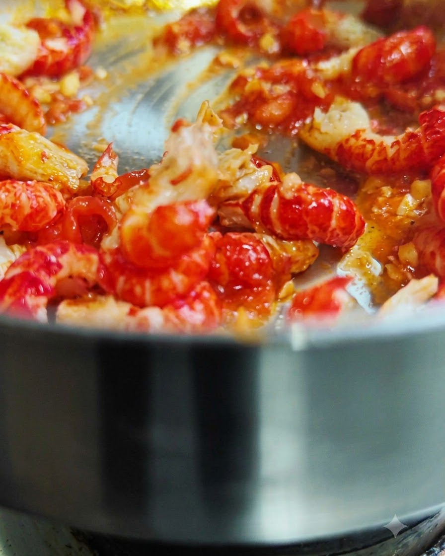 Code di gamberi sgusciate saltate in una padella calda con salsa di pomodoro rossa.