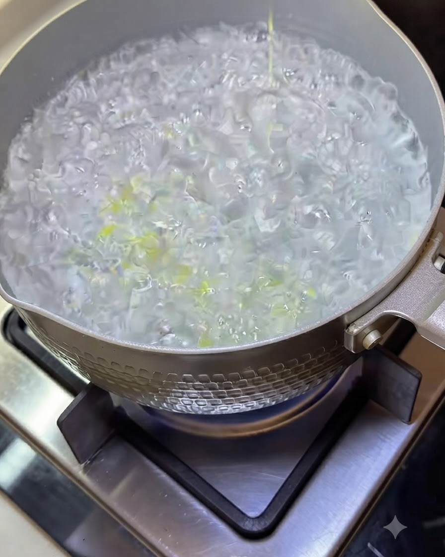 Spaghetti in cottura in una pentola di acqua bollente con liquido ribollente.