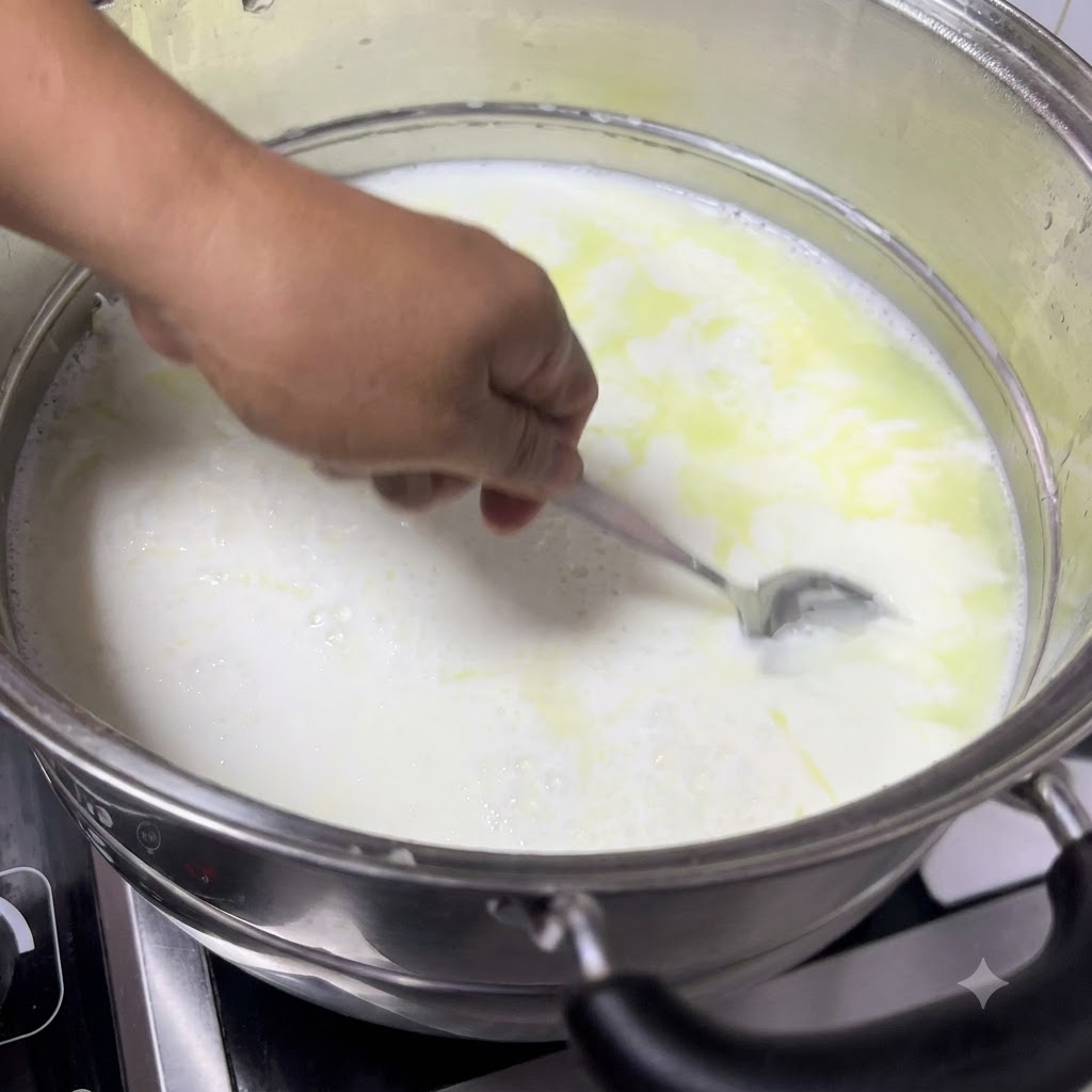 Un cucchiaio che raccoglie il latte cagliato dalla pentola, mostrando soffici cagliate bianche che si separano dal siero giallastro.