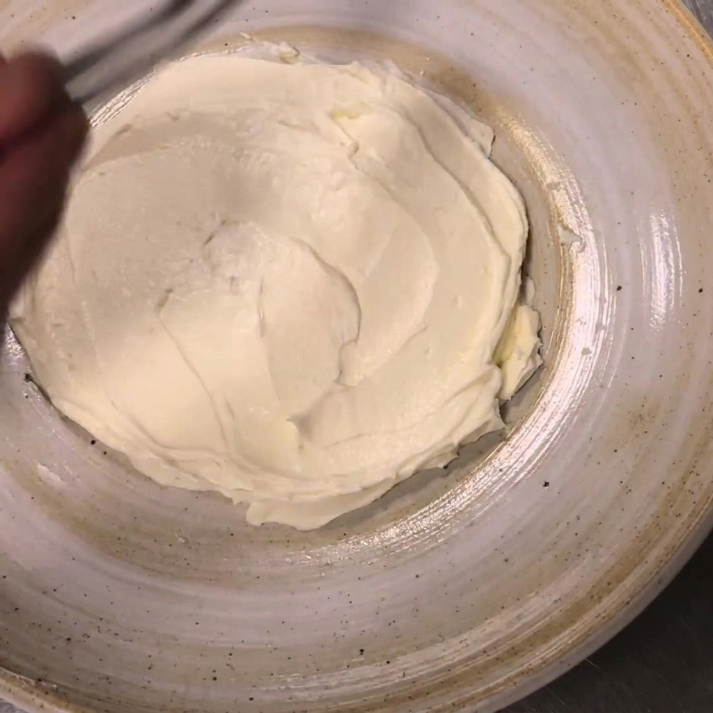Metà di pomodorini posizionate attorno ai bordi della ricotta spalmata usando pinzette da cucina.