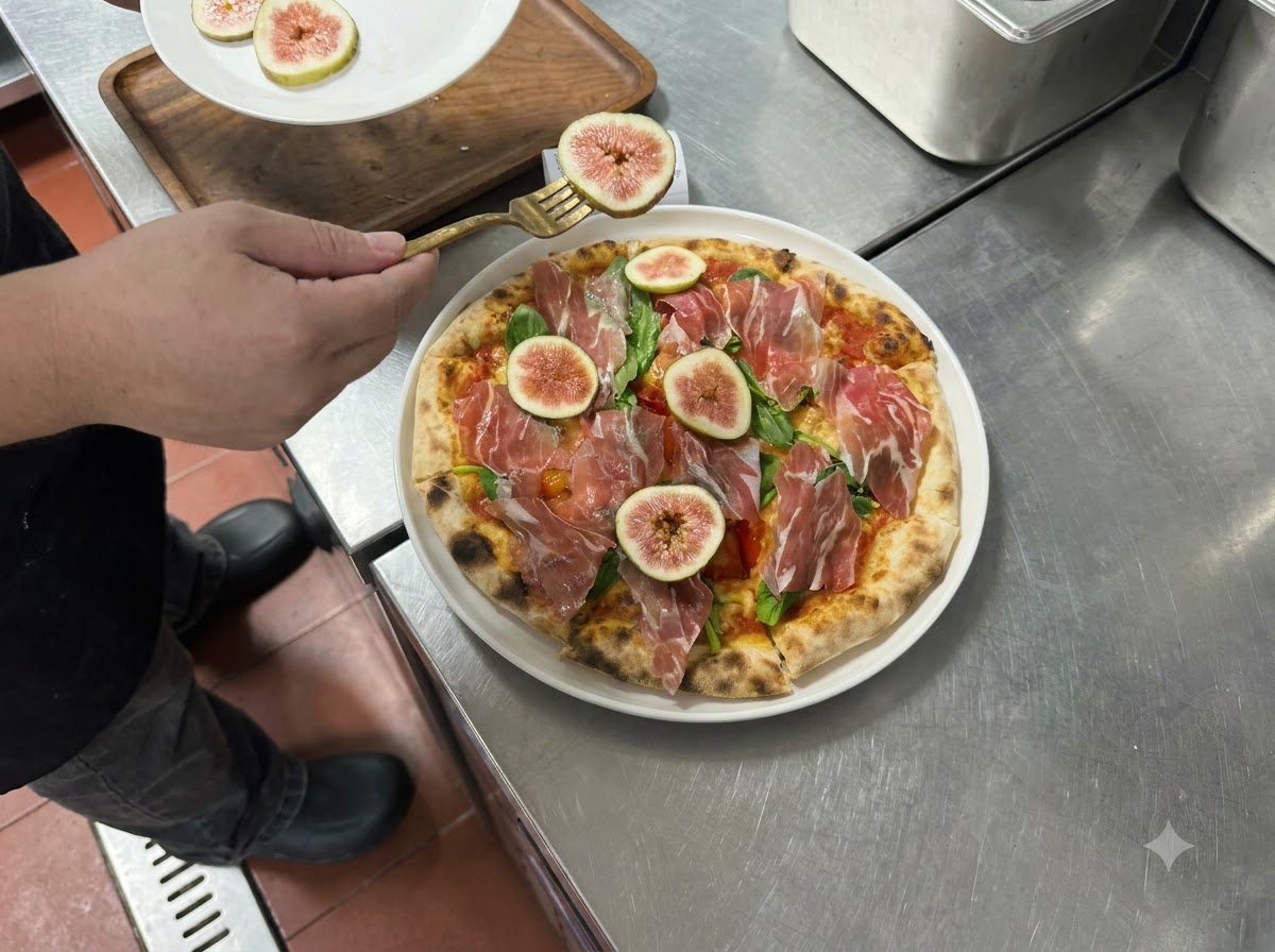 Fette di fichi freschi e prosciutto disposte sopra la pizza cotta con laiuto di una forchetta.