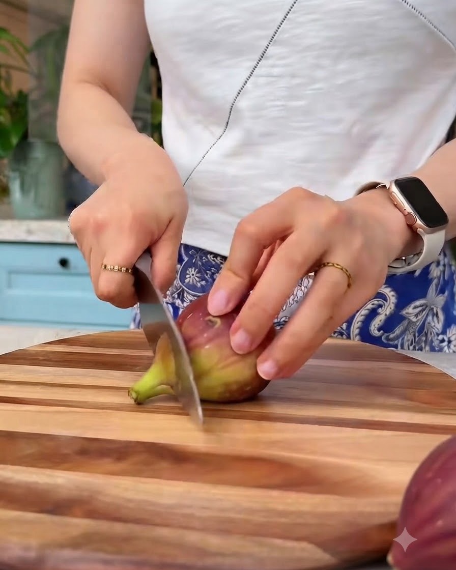 Fichi freschi tagliati a piccoli pezzi con un coltello su un tagliere di legno.