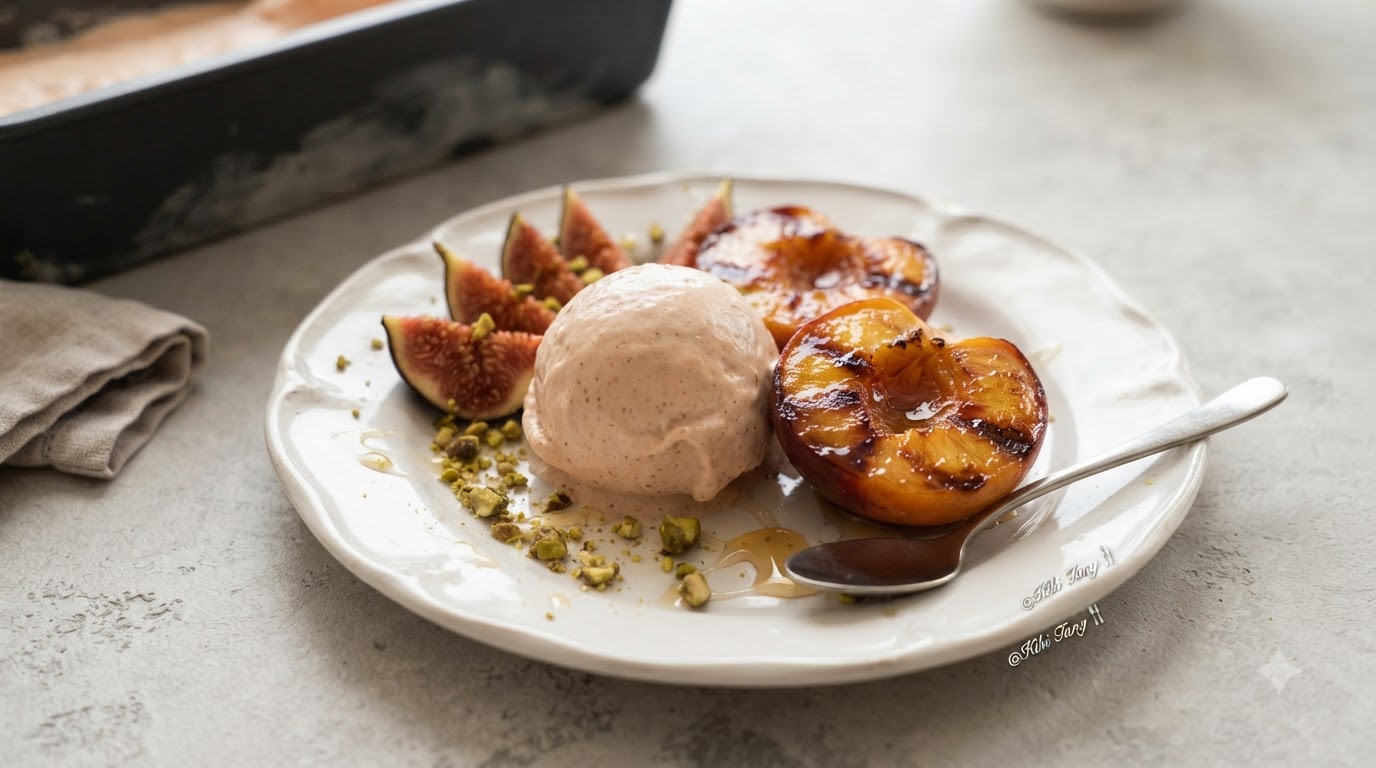 Una pallina di gelato cremoso ai fichi e rum servita con metà pesche calde arrostite alla cannella e granella di pistacchi.