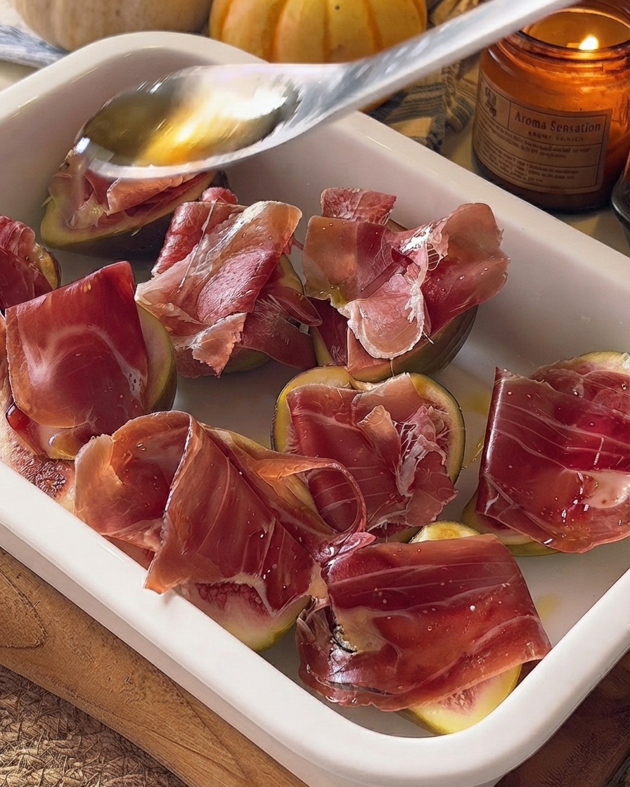 Miele versato da un cucchiaio sui fichi e sul prosciutto preparati in una pirofila.