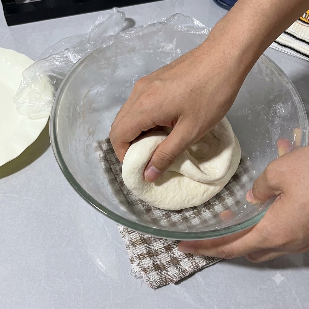 Mani spruzzate con acqua che piegano limpasto allinterno della ciotola di vetro coperta con pellicola trasparente.