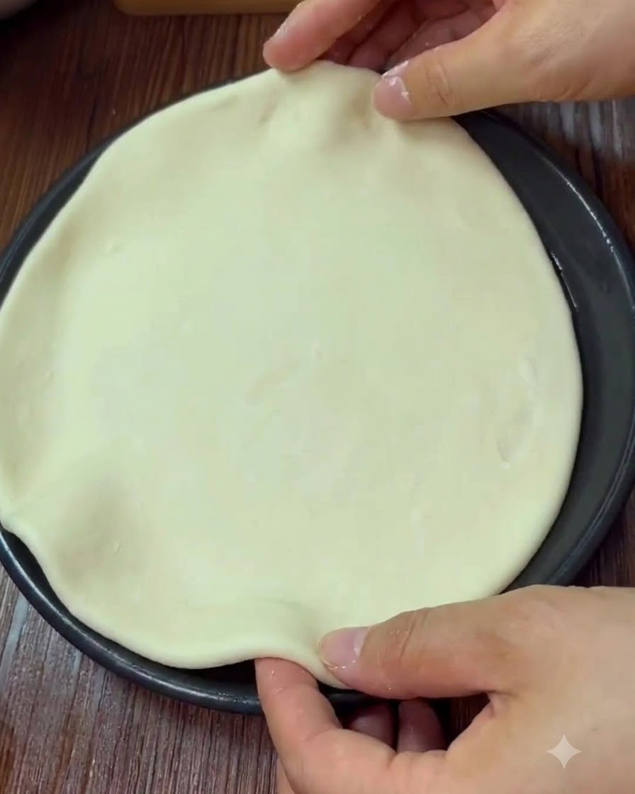 Mani che modellano e pizzicano il bordo della pizza allinterno di una teglia.