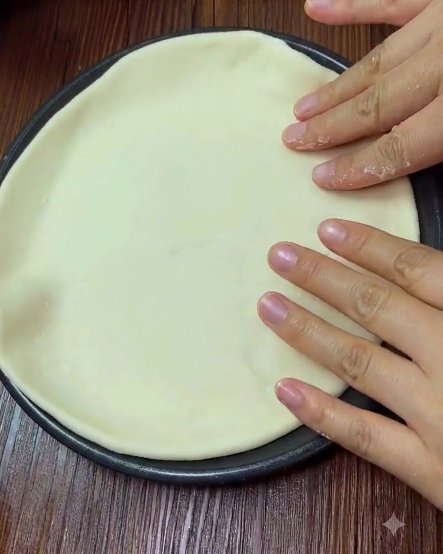 Mani che premono delicatamente sulla superficie della pasta della pizza stesa.