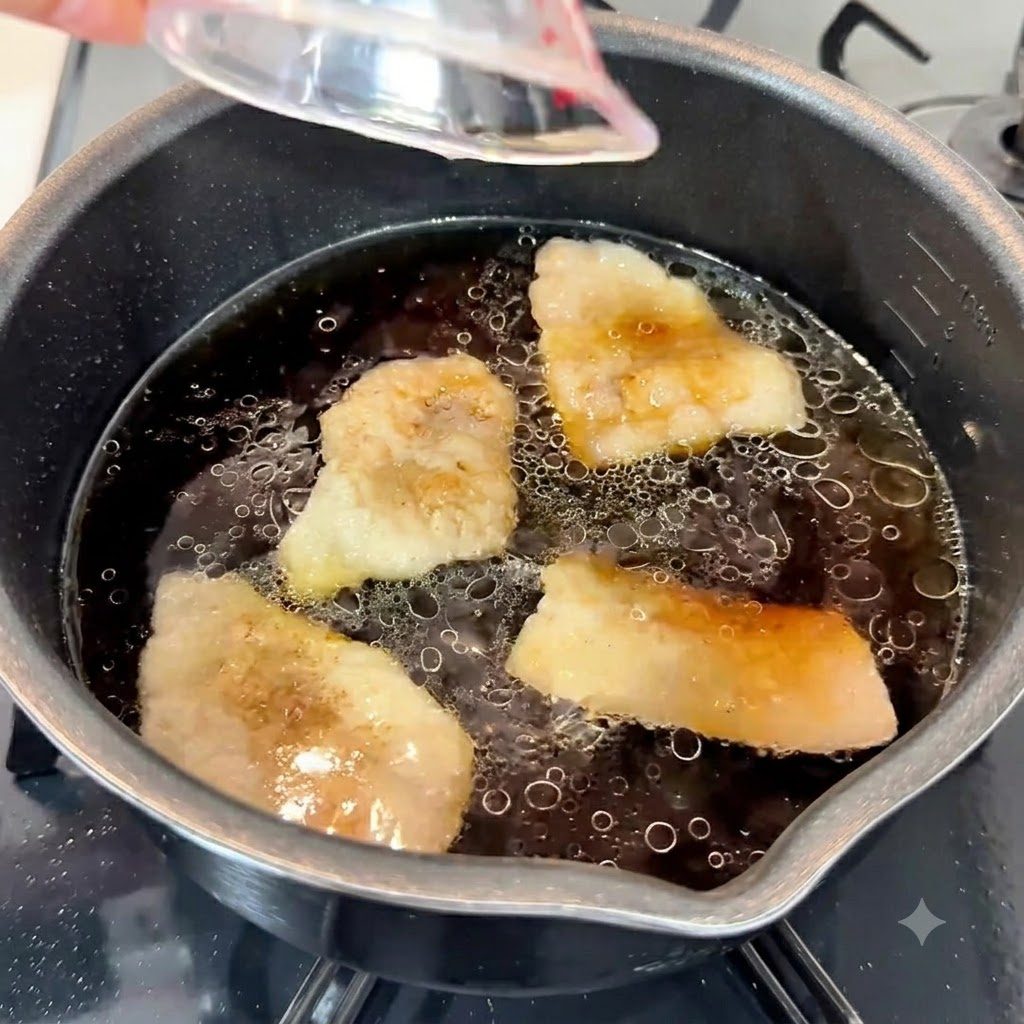 Pasta di aglio, olio di sesamo e zucchero bianco versati nella ricca base di zuppa scura in una pentola.