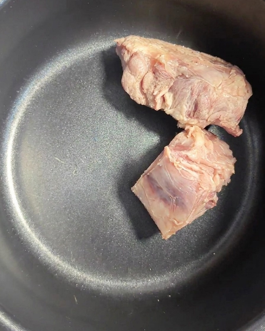 Ossa di maiale sciacquate allinterno di una pentola scura da cuociriso.
