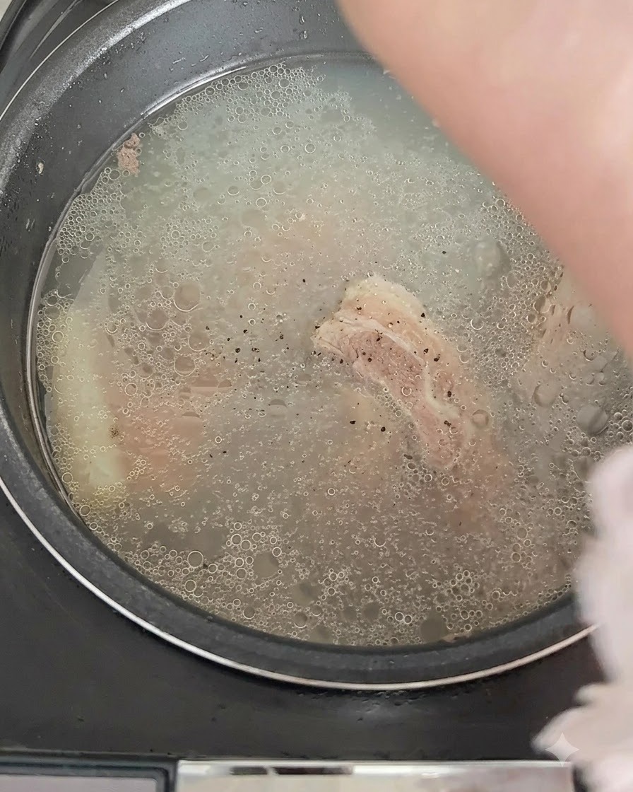 Pepe nero cosparso sul brodo in ebollizione nel cuociriso.