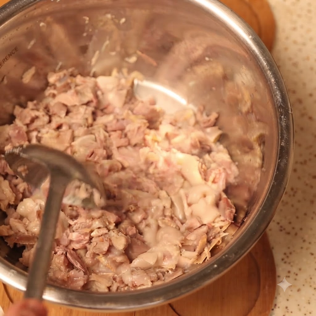 Carne di maiale cotta accuratamente schiacciata in una grande ciotola da cucina.