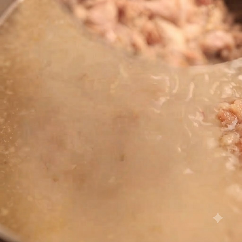 Ricco brodo di ossa di maiale bianco latte filtrato attraverso un setaccio a maglia fine per catturare i pezzetti di carne rimanenti.