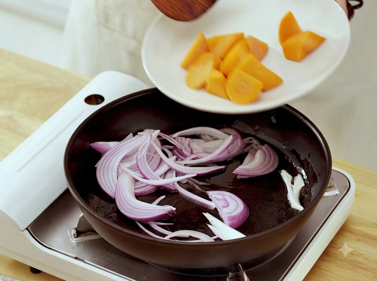 Pezzi di carota trasferiti da un piatto bianco in una padella contenente strisce di cipolla saltate.