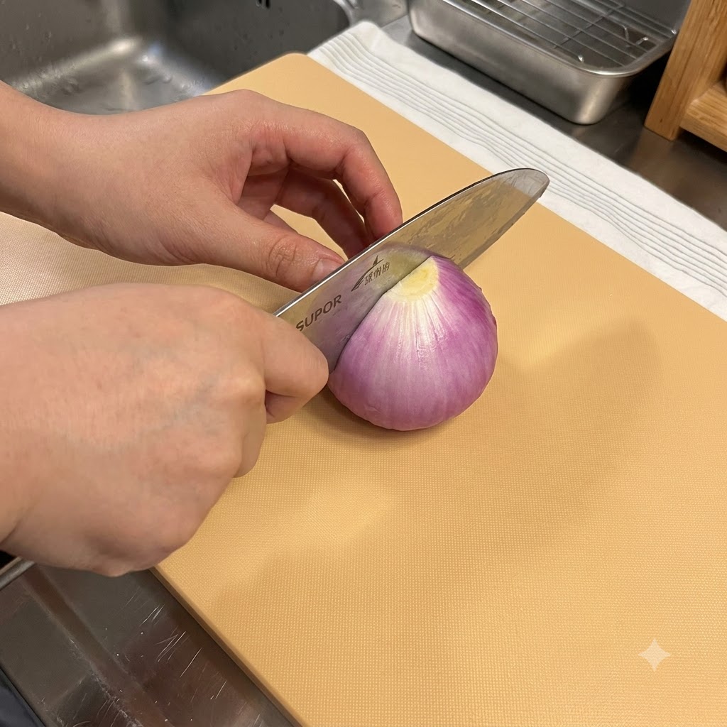 Un coltello da cucina che taglia una cipolla rossa su un tagliere di legno.