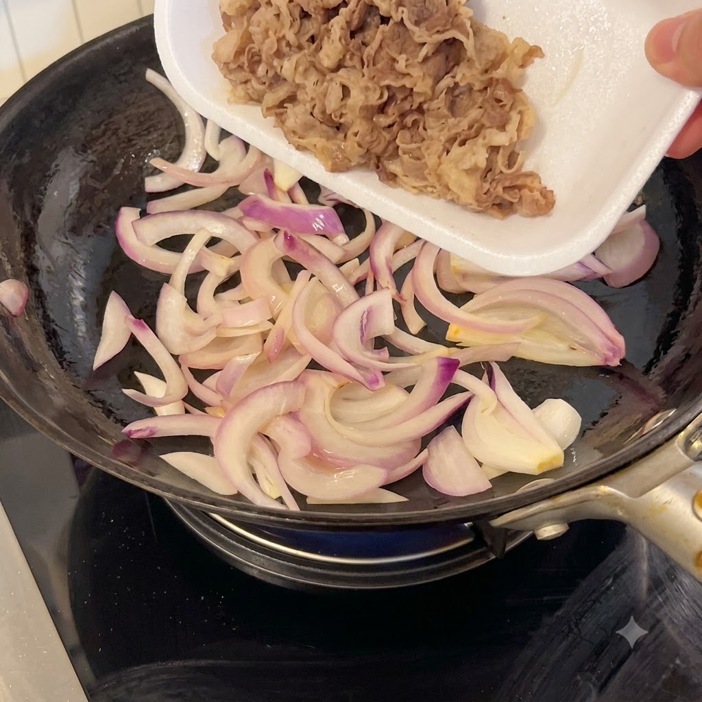 Manzo tagliato sottile versato da un vassoio bianco in una padella con cipolle rosse saltate.